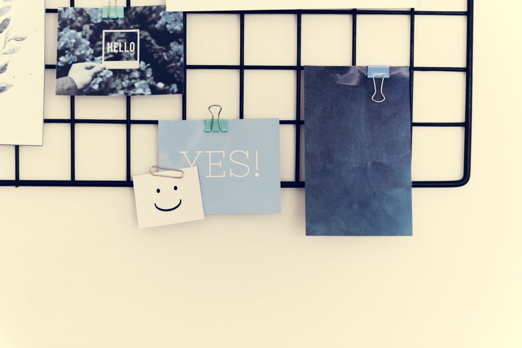 Postcard and Pictures on a Rack Against a White Wall