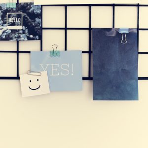 Postcard and Pictures on a Rack Against a White Wall